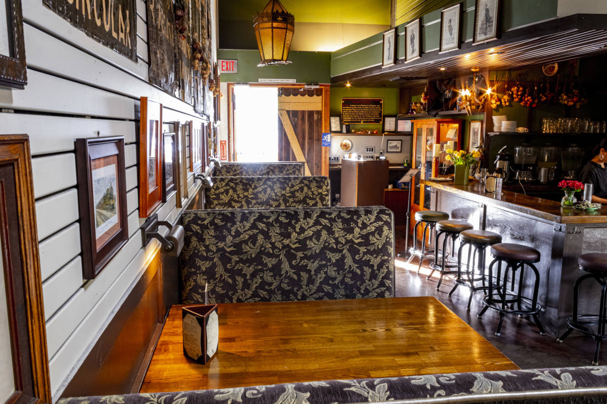 Restaurant interior, tables lined up, bar area in the back